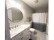 A well-lit bathroom featuring a marble vanity, round mirror, gray tile floor, and a shower/tub combo at 8201 E 250 S, Zionsville, IN 46077