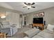 Comfortable living room featuring neutral walls, ceiling fan, and an entertainment center with a large television at 12658 Watford Way, Fishers, IN 46037