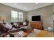 Inviting living room with hardwood floors, a comfortable leather sofa, and a large window for natural light at 12658 Watford Way, Fishers, IN 46037