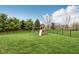 A lush backyard featuring a wooden swing set with slide and playhouse surrounded by trees at 13974 Nina Dr, Carmel, IN 46074