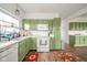 A well-lit kitchen featuring green cabinets, white appliances, and modern flooring at 2416 Meadow Bend Dr, Columbus, IN 47201