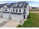 A charming new two-story townhome featuring white siding, black accents, an attached two-car garage, and a well-manicured lawn at 3240 Arabian Ln, Zionsville, IN 46077