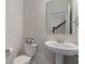 Bright powder room featuring a pedestal sink, toilet, and view of the staircase through the mirror at 3240 Arabian Ln, Zionsville, IN 46077