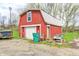 Red barn with a white garage door, a green waste container, and various items around it at 3360 E Main St, Danville, IN 46122