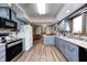 Updated kitchen features blue cabinets, an island, modern appliances, and wood-look flooring at 3360 E Main St, Danville, IN 46122