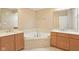 Bright bathroom featuring double vanity sinks, soaking tub, and neutral-toned tile at 355 E Ohio St # 309, Indianapolis, IN 46204