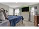 Bedroom featuring blue bedding, dresser, mounted TV, and a window for natural light at 371 Bluestem Ln, Whiteland, IN 46184