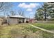 View of the backyard with weathered shed, red outbuilding, and mature trees on a partly cloudy day at 443 S Arlington Ave, Indianapolis, IN 46219