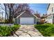 Detached garage with a wide driveway and a picturesque tree with colorful blossoms at 4849 Central Ave, Indianapolis, IN 46205