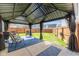 View of backyard patio with seating and privacy drapes overlooking the yard at 6953 Beargrass Ct, Indianapolis, IN 46241