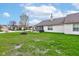 View of the backyard with green grass, a small tree, and the back of the house with a chimney at 7150 Brant Pointe Cir, Indianapolis, IN 46217