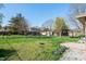 This backyard features mature trees, a chainlink fence, and a grassy area, with neighboring houses in view at 745 W Banta Rd, Indianapolis, IN 46217