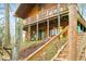 Exterior shot of the log cabin featuring a wrap-around porch, and stairs to the dock that provide lake access at 7591 Inkbush Dr, Nineveh, IN 46164