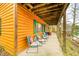 Spacious covered porch with cozy seating area, showcasing the log cabin's wood design and natural green trim at 7591 Inkbush Dr, Nineveh, IN 46164