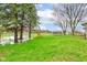 Spacious backyard featuring mature trees, lush green lawn, and fun playground equipment at 7764 S State Road 109, Markleville, IN 46056