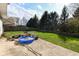 Spacious backyard with a lush lawn, wood logs, and a blue kiddie pool on the concrete patio at 8424 Nuckols Ln, Indianapolis, IN 46237
