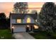 Inviting exterior view of a two-story home with a front porch, garage, and beautifully lit windows at sunset at 8424 Nuckols Ln, Indianapolis, IN 46237