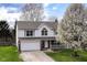 Charming two-story home with a well-manicured lawn, inviting porch, attached garage, and beautiful flowering trees at 8424 Nuckols Ln, Indianapolis, IN 46237