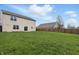 Large grassy backyard with wooden fence, a sliding glass door, and clear blue skies at 10016 Jenna Ln, Indianapolis, IN 46239