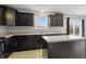 Kitchen featuring black appliances, dark cabinets, and neutral countertops, centered around a functional island at 10016 Jenna Ln, Indianapolis, IN 46239