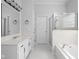 Bathroom featuring white cabinets, double sinks, a glass-enclosed shower, and a luxurious soaking tub at 10109 Fergus Ave, Carmel, IN 46032
