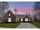 Elegant brick home with a curved driveway, bay windows, and lush landscaping under a vibrant sky at 10109 Fergus Ave, Carmel, IN 46032