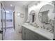 Well-lit bathroom featuring double sinks, decorative mirrors, and an adjacent tub area at 1127 Island Woods Dr # 56, Indianapolis, IN 46220