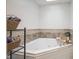 Bathroom featuring a corner jacuzzi tub, storage shelves, and a decorative tile border at 1127 Island Woods Dr # 56, Indianapolis, IN 46220