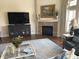 A cozy living room featuring a fireplace with a stone surround, a TV, hardwood floors and a blue accent chair at 11863 Edgefield Dr, Fishers, IN 46037