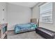 A gray carpeted bedroom with a tufted bed, window, and ottoman at 1407 Allen Ct, Shelbyville, IN 46176