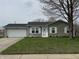 Charming single story home with green lawn and a two-car garage, enhanced by a mature shade tree at 1424 Ashley Dr, Lebanon, IN 46052
