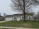 Charming single story home with green lawn and a two-car garage, enhanced by a mature shade tree at 1424 Ashley Dr, Lebanon, IN 46052