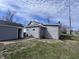 This image showcases the home's backyard, featuring gray siding, a separate garage, and ample yard space at 1445 S Belmont Ave, Indianapolis, IN 46221