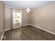 Cozy bedroom featuring wood-look floors, neutral walls, and a window overlooking the landscaped front yard at 1509 Copperwood Pl, Carmel, IN 46033