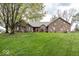 Charming brick home features a lush green lawn, mature trees, and a welcoming red front door at 1509 Copperwood Pl, Carmel, IN 46033