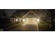 Charming home exterior with a two-car garage, covered porch, manicured lawn, and flowering trees at night at 15129 Smithfield Dr, Westfield, IN 46074