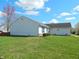 Side view of a one-story home with tidy landscaping, blue window frames, and a green lawn at 1643 Kayla Dr, Indianapolis, IN 46234