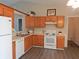 Well-lit kitchen with wooden cabinets, white appliances, and views into other areas of the home at 1643 Kayla Dr, Indianapolis, IN 46234