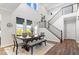 Dining area beneath tall ceilings shows the staircase and a modern rustic dining table set with decorative centerpiece at 16688 Bowesmont Dr, Fortville, IN 46040