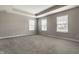 Spacious carpeted bedroom showcasing a tray ceiling, neutral walls, and multiple windows for abundant natural light at 17372 Graley Pl, Westfield, IN 46074