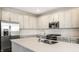 Close-up of kitchen island with stainless steel refrigerator, gas range, and white cabinets at 17372 Graley Pl, Westfield, IN 46074