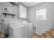Well-lit laundry room features a full-size washer and dryer, storage cabinet, and wooden-look flooring at 218 Urban St, Danville, IN 46122