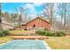 Inviting backyard featuring a covered pool, brick house, wooden deck, mature trees, and lush greenery for outdoor enjoyment at 251 E South St, Franklin, IN 46131