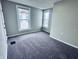 This bedroom has neutral paint, carpet, two windows, and baseboard trim at 310 N Monroe St, Muncie, IN 47305