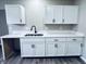 Kitchen featuring a stainless steel sink with white cabinets, countertops, and black hardware at 310 N Monroe St, Muncie, IN 47305