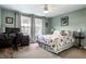 A comfortable bedroom with a floral patterned bedspread, a work desk, and bright, sunlit windows at 3393 Paisley Pointe, Whitestown, IN 46075