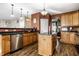 Bright kitchen featuring an island, wood cabinets, stainless steel appliances, and modern lighting fixtures at 3393 Paisley Pointe, Whitestown, IN 46075