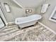 Elegant bathroom features a clawfoot tub, modern flooring, and stylish fixtures, complemented by soft natural light at 4205 Rookwood Ave, Indianapolis, IN 46208
