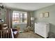 Bright Bedroom featuring a crib, changing table, and chair with natural light from a large window at 5311 Larita Ln, Anderson, IN 46017