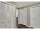 Hallway with multiple closet spaces featuring white closet doors, neutral paint, and wood floors at 5311 Larita Ln, Anderson, IN 46017